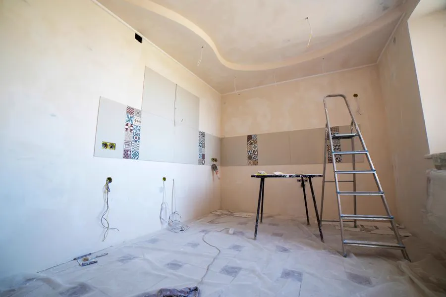 Room mid-renovation with fresh drywall, new tiling and a step ladder