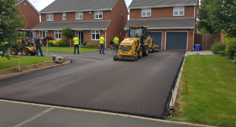 Completed paving project — fresh driveway with crew on site